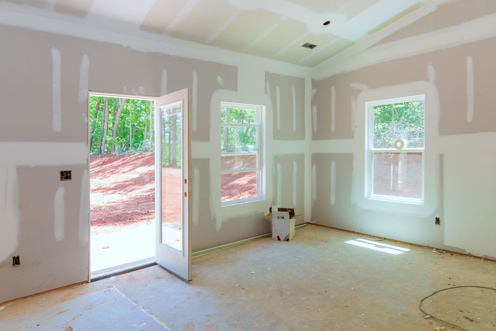 Living room in-progress construction showing unfinished walls during residential drywall installation by a professional drywall contractor